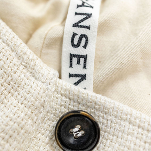 Hansen Garments Bobby Wide Pleated Trousers - Off White Gauze - product shot - close up - detail of brand tag, fabric, and button