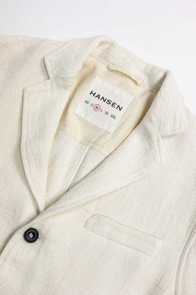 Hansen Garments Charlie Three Button Blazer - Off White Gauze - product shot - front facing - close up detail of brand tag, collar, and button - white backdrop