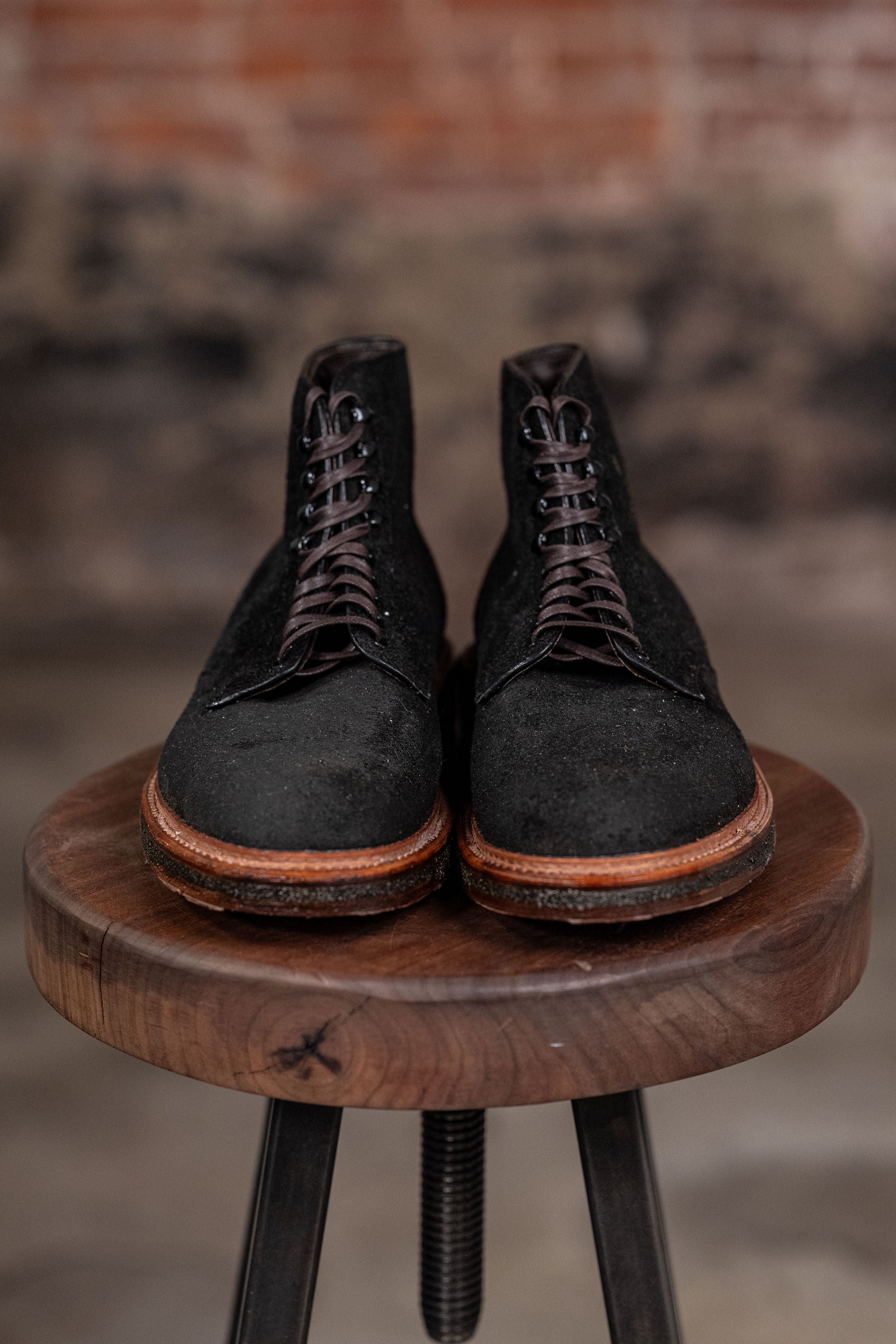 Alden Plain Toe boots on a wooden stool with a blurred background - front view