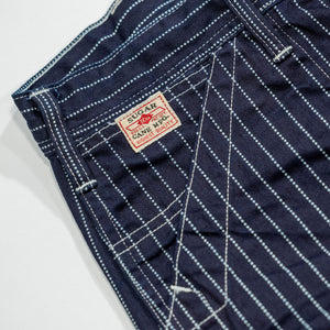 Navy striped fatigue pocket pants close up on right front pocket with white/red Sugar Cane logo laying flat