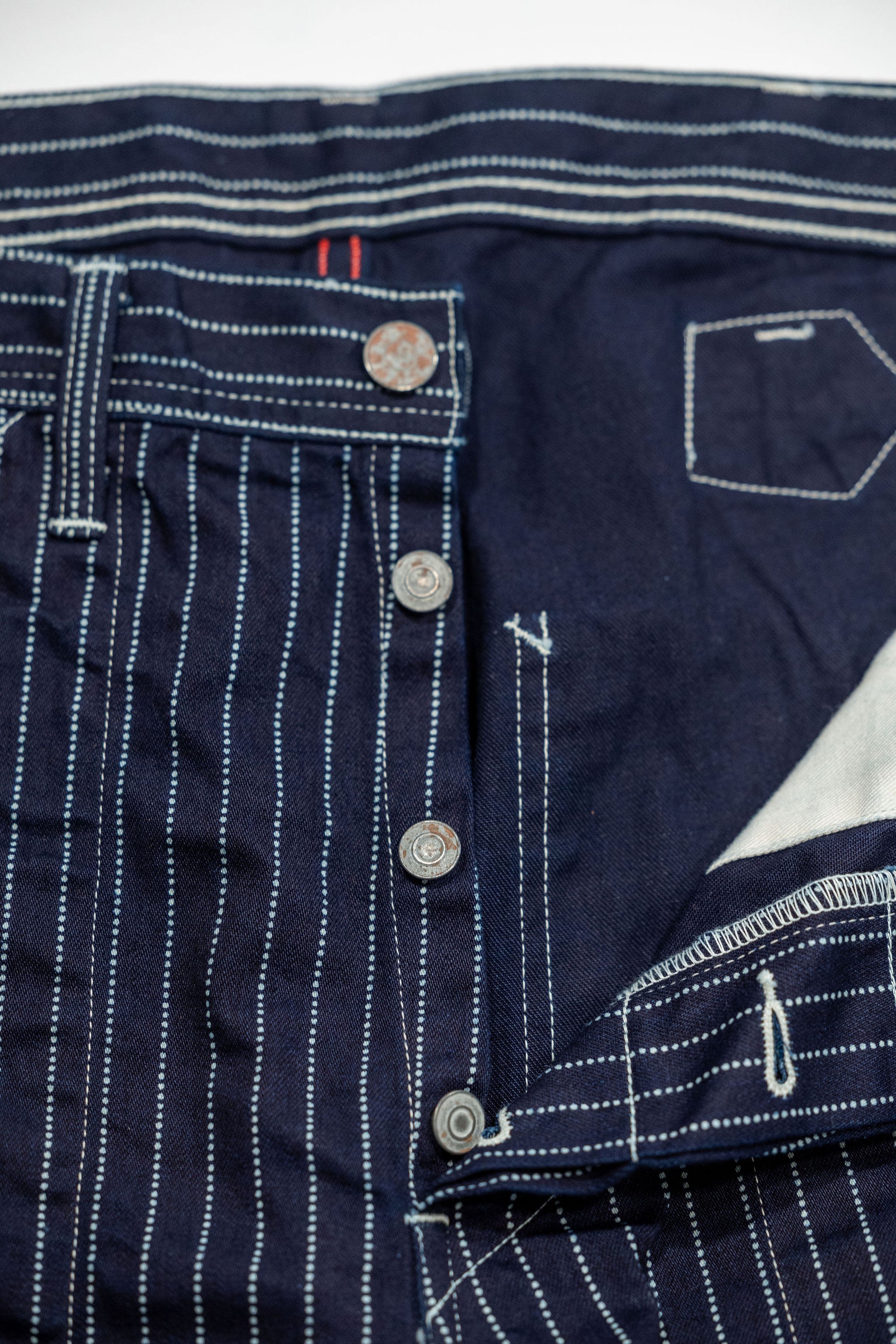 Navy striped fatigue pocket pants close up on open button fly laying flat