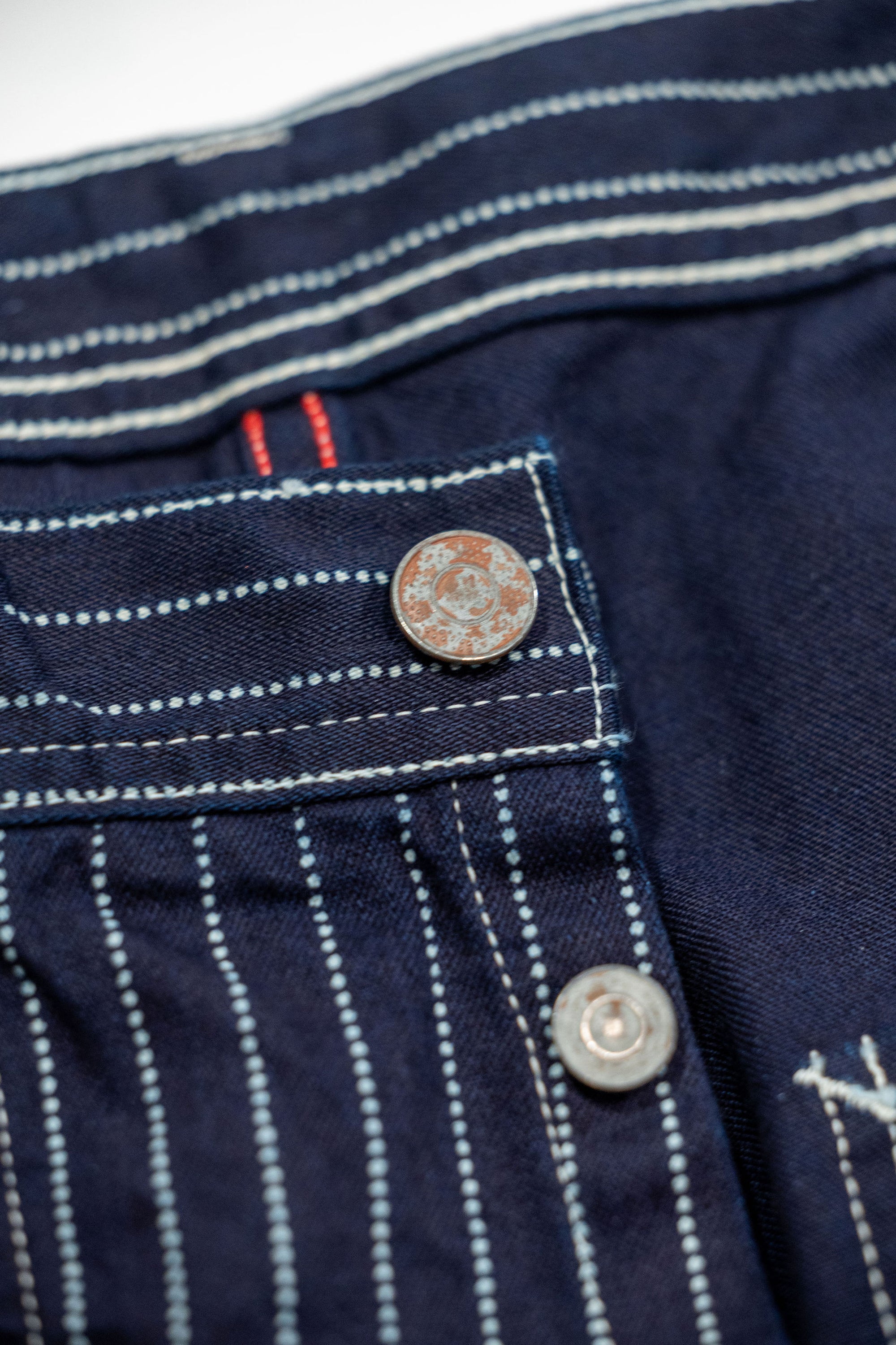 Navy striped fatigue pocket pants close up on rtop button laying flat