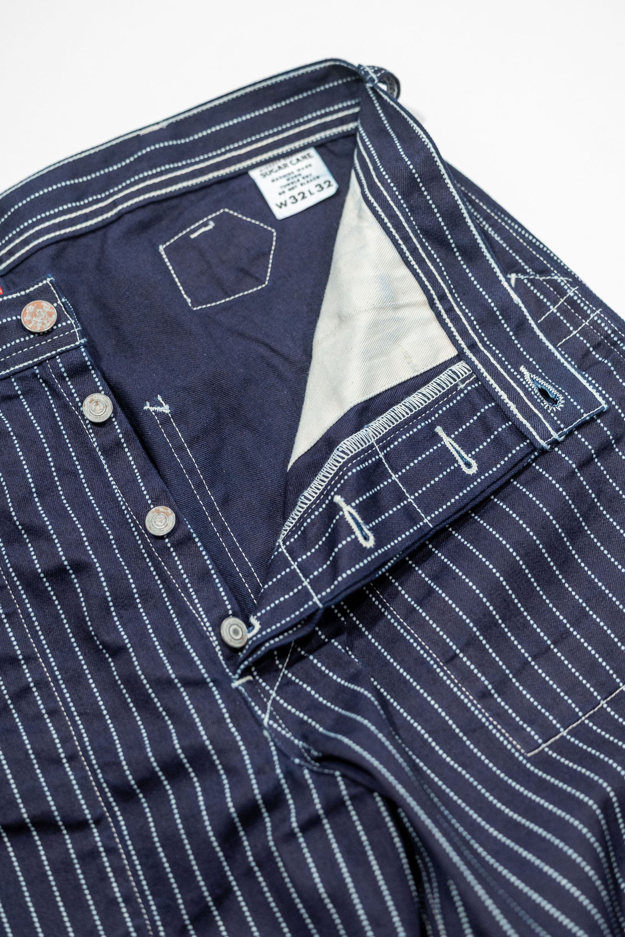 Navy striped fatigue pocket pants close up on open fly and thigh with solid navy interior laying flat