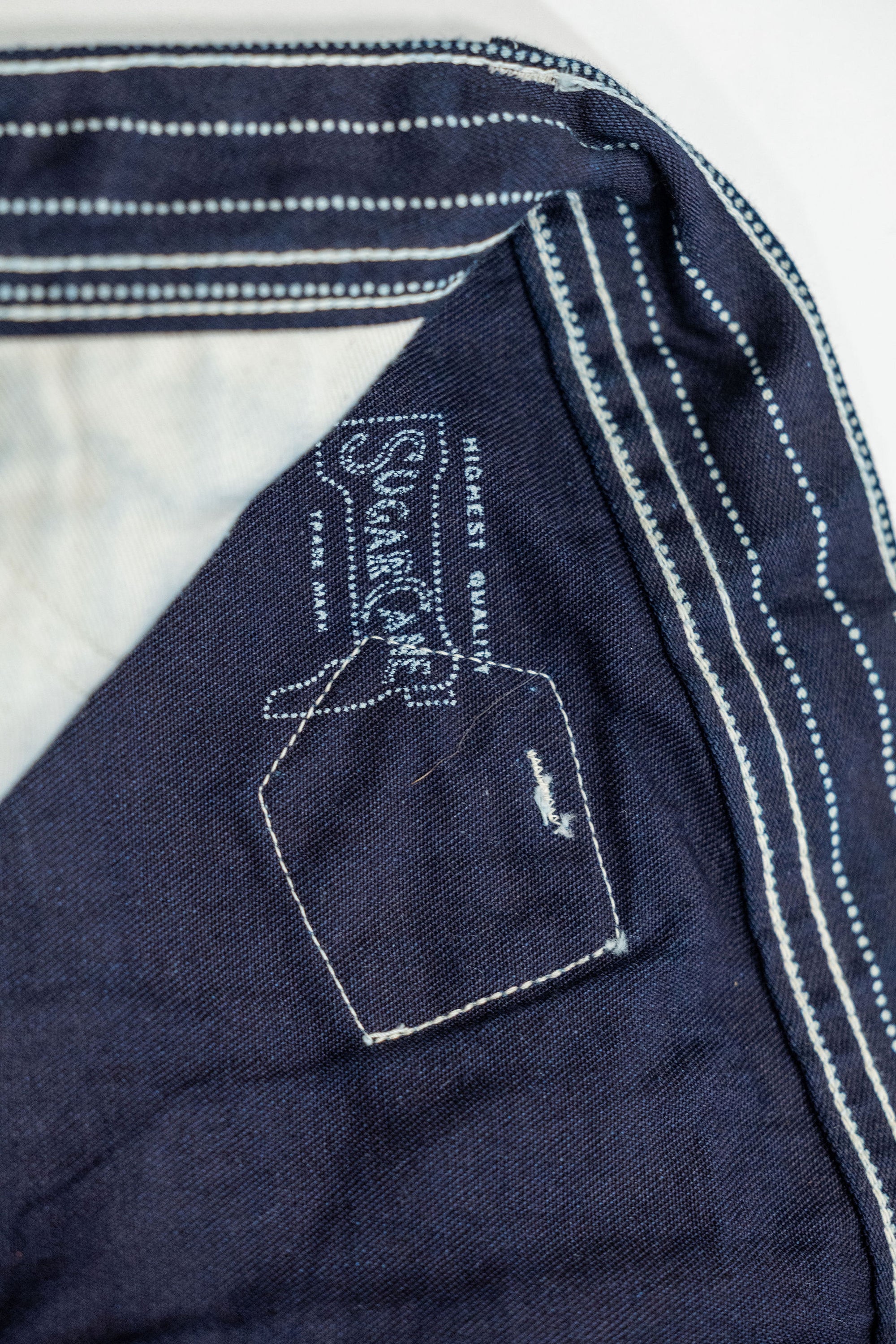 Navy striped fatigue pocket pants close up on solid navy interior and internal Sugar Cane branding laying flat