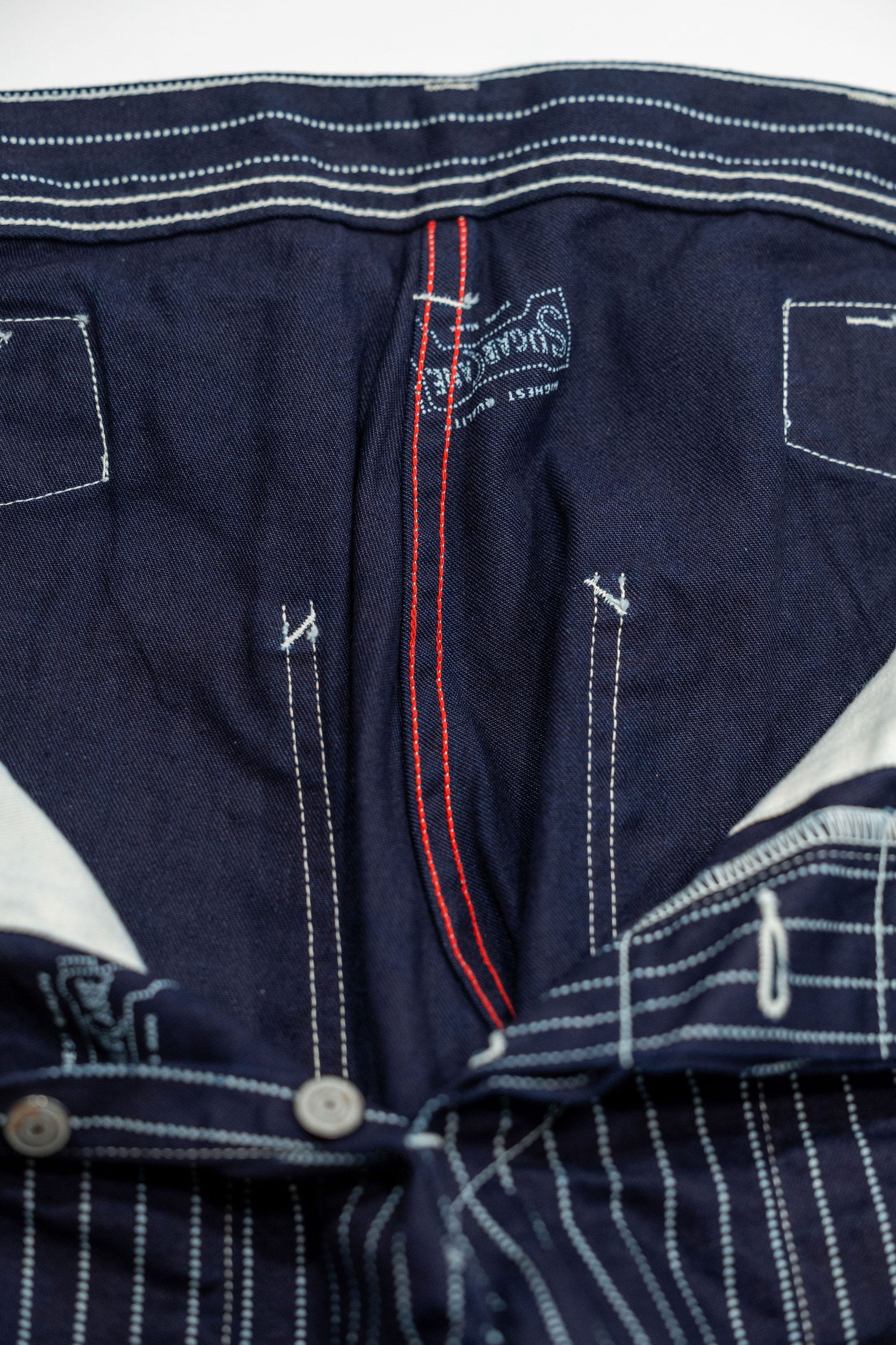Navy striped fatigue pocket pants close up on solid navy interior and red internal stitching laying flat