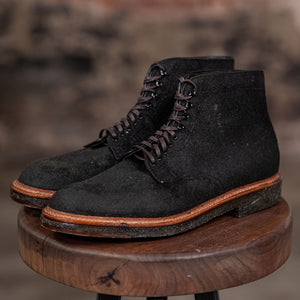 Alden Plain Toe boots on a wooden stool with a brick wall background - three quarter view