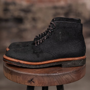 Alden Plain Toe boots on a wooden stool with a brick wall background - side view