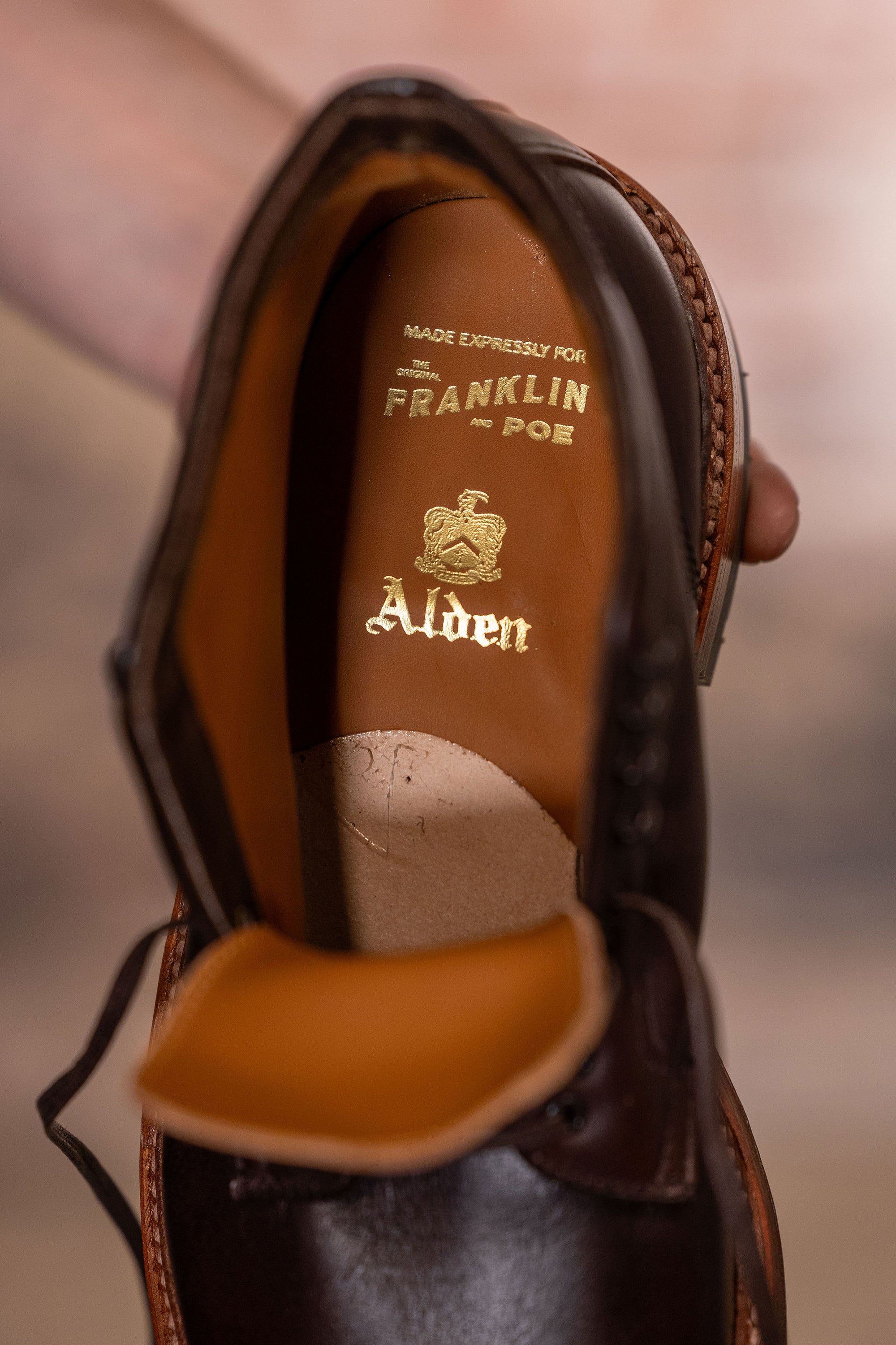 Brown leather cap toe boots closeup on Alden and Franklin and Poe branding on tan leather insole