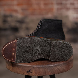Alden Plain Toe boots on a wooden stool against a brick wall - view of sole