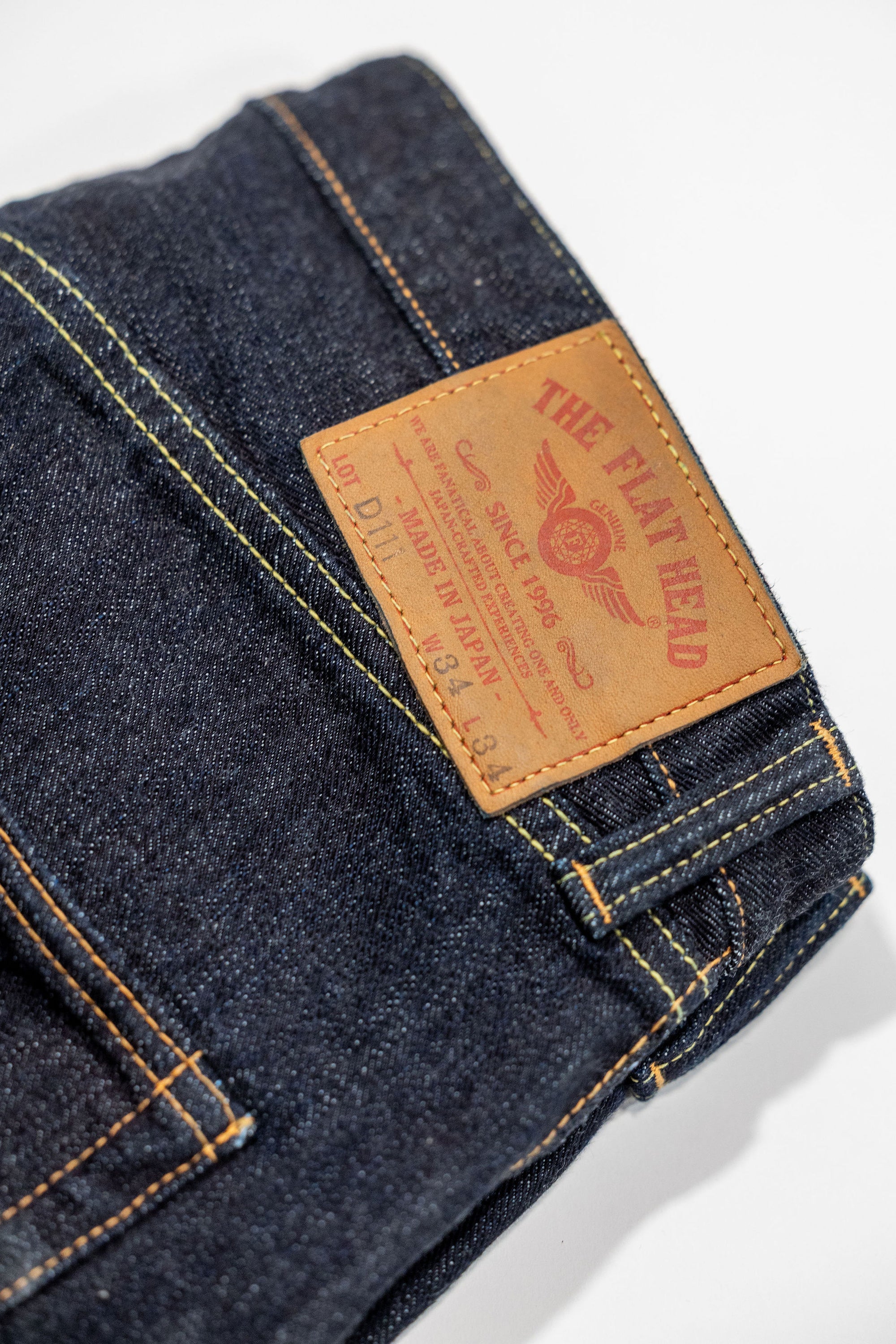 Indigo denim jeans wide cut back view laying flat close up on leather patch