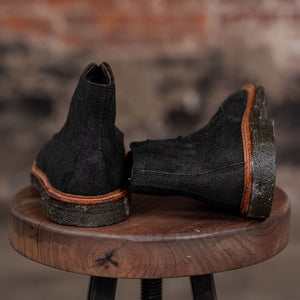 Pair of Alden Plain Toe boots on a wooden stool with a blurred background - back view