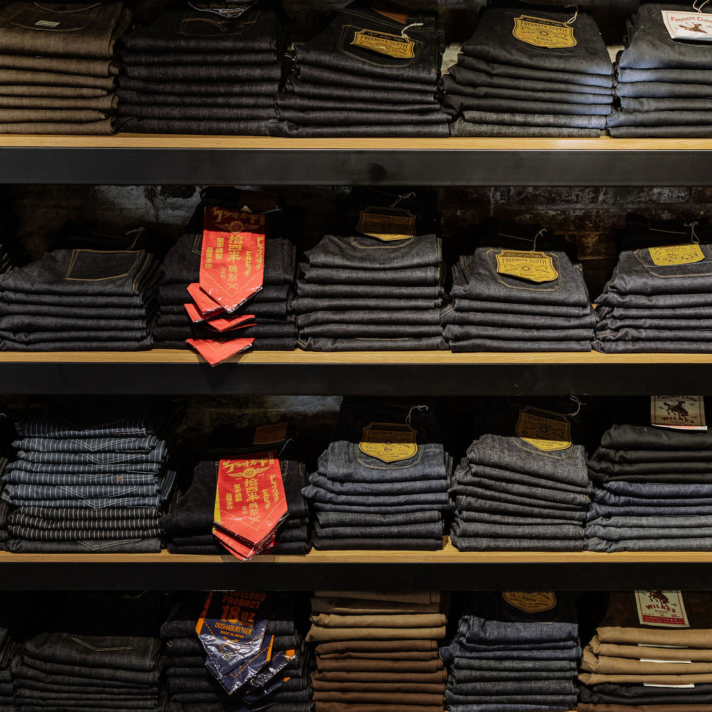 Image of the denim wall at Franklin and Poe. 4 rows of folded and stacked denim.