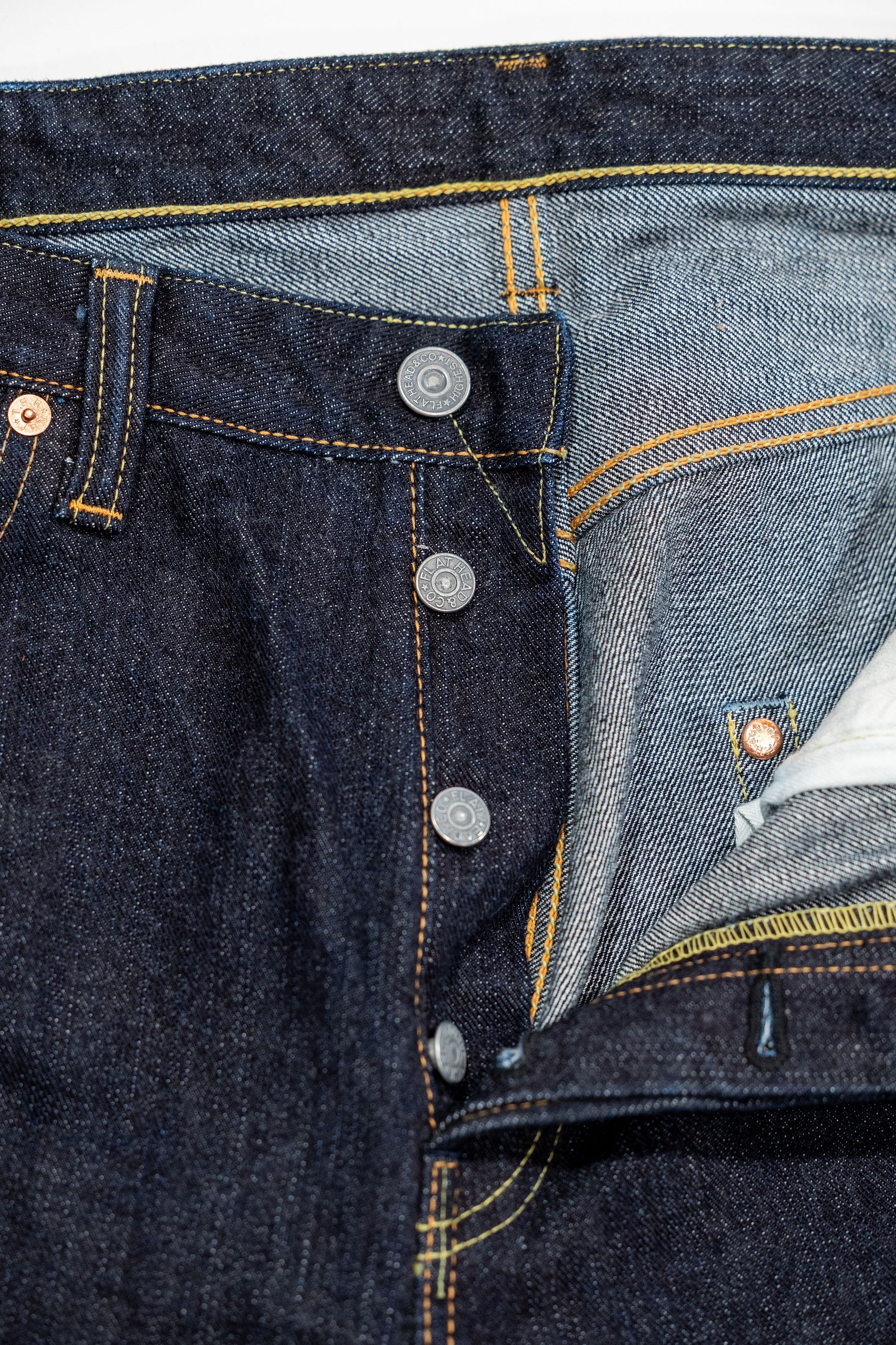 Indigo denim jeans wide cut front view laying flat closeup on open fly