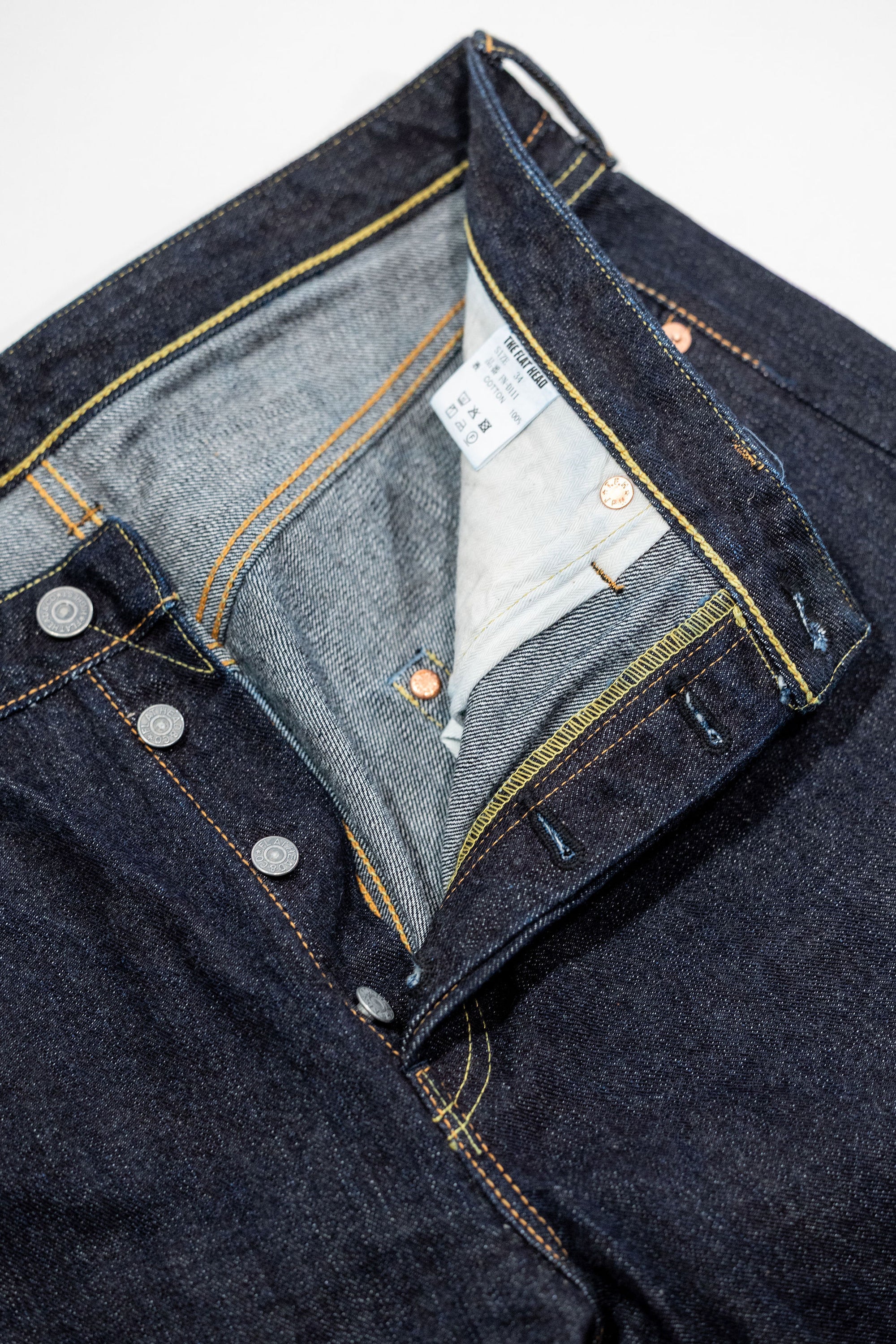 Indigo denim jeans wide cut front view laying flat close up on open fly
