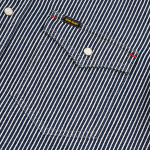 Western style shirt with indigo and white thin vertical stripes and white snaps close-up on pocket