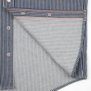 Western style shirt with indigo and white thin vertical stripes and white snaps close-up on snaps and both sides of fabric