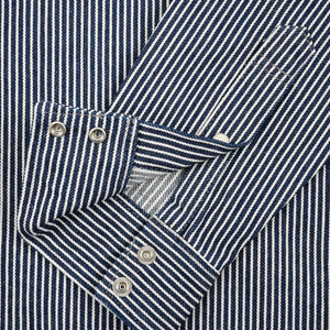 Western style shirt with indigo and white thin vertical stripes and white snaps close-up on sleeve unbuttoned