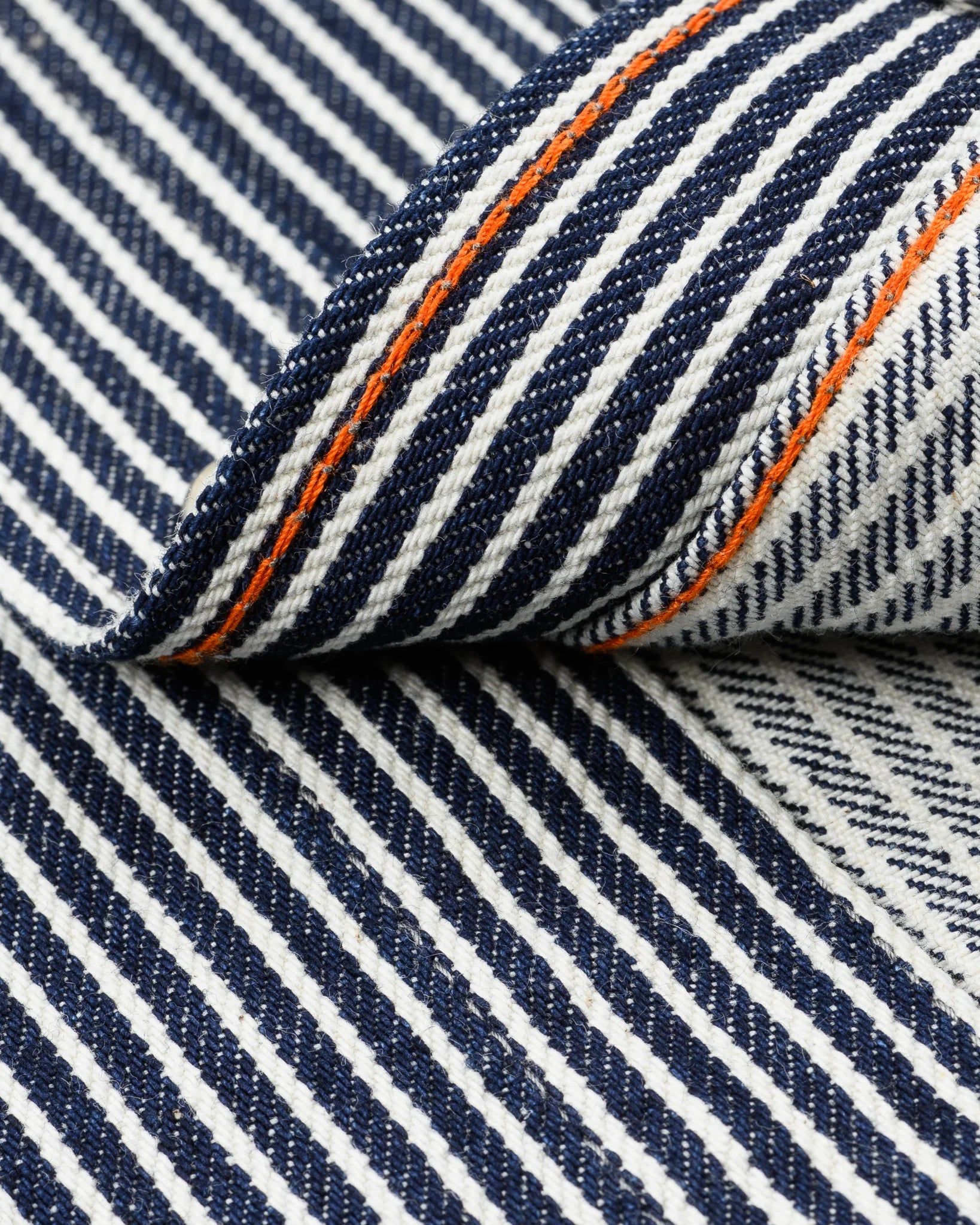 Western style shirt with indigo and white thin vertical stripes close-up on fabric and orange bottom stitch 