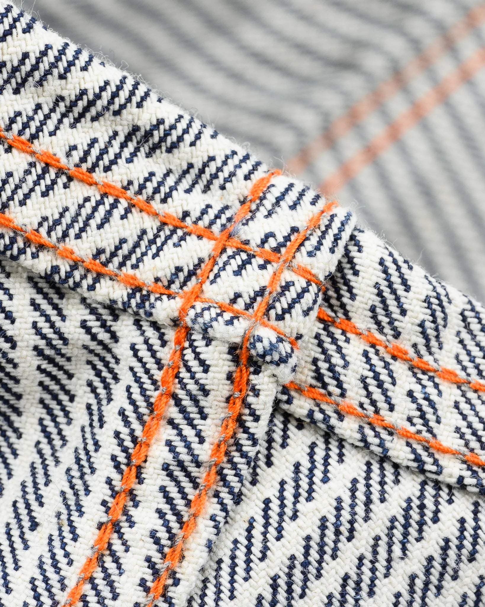 Western style shirt with indigo and white thin vertical stripes close-up on underside of fabric and orange bottom stitch 
