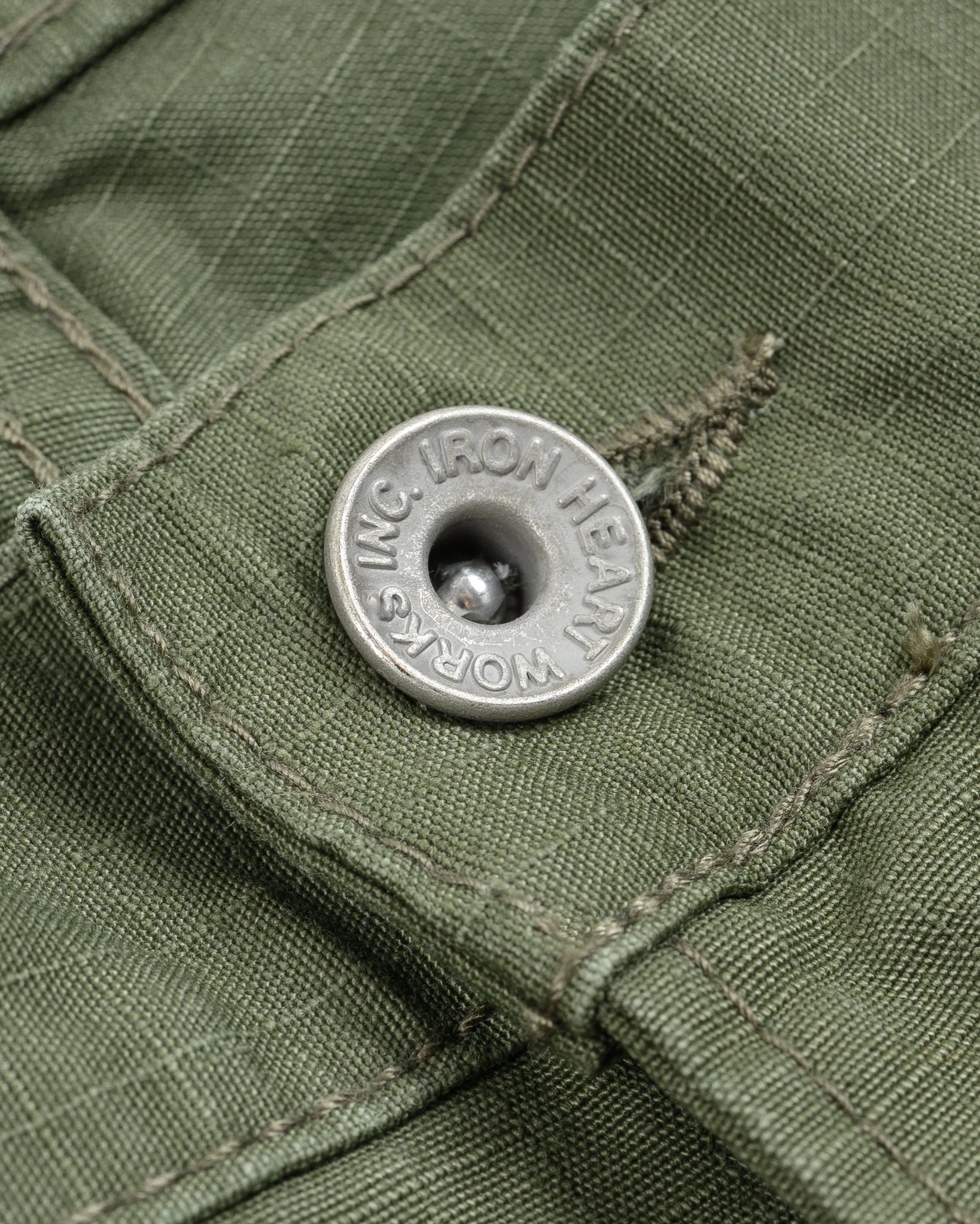 Olive pants laying flat closeup on metal button