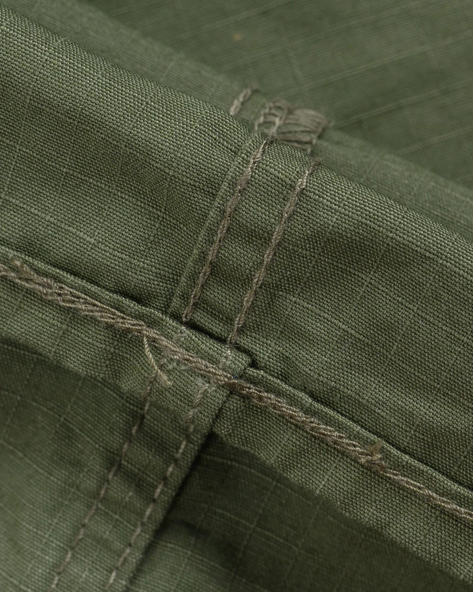 Olive pants laying flat closeup on stitching
