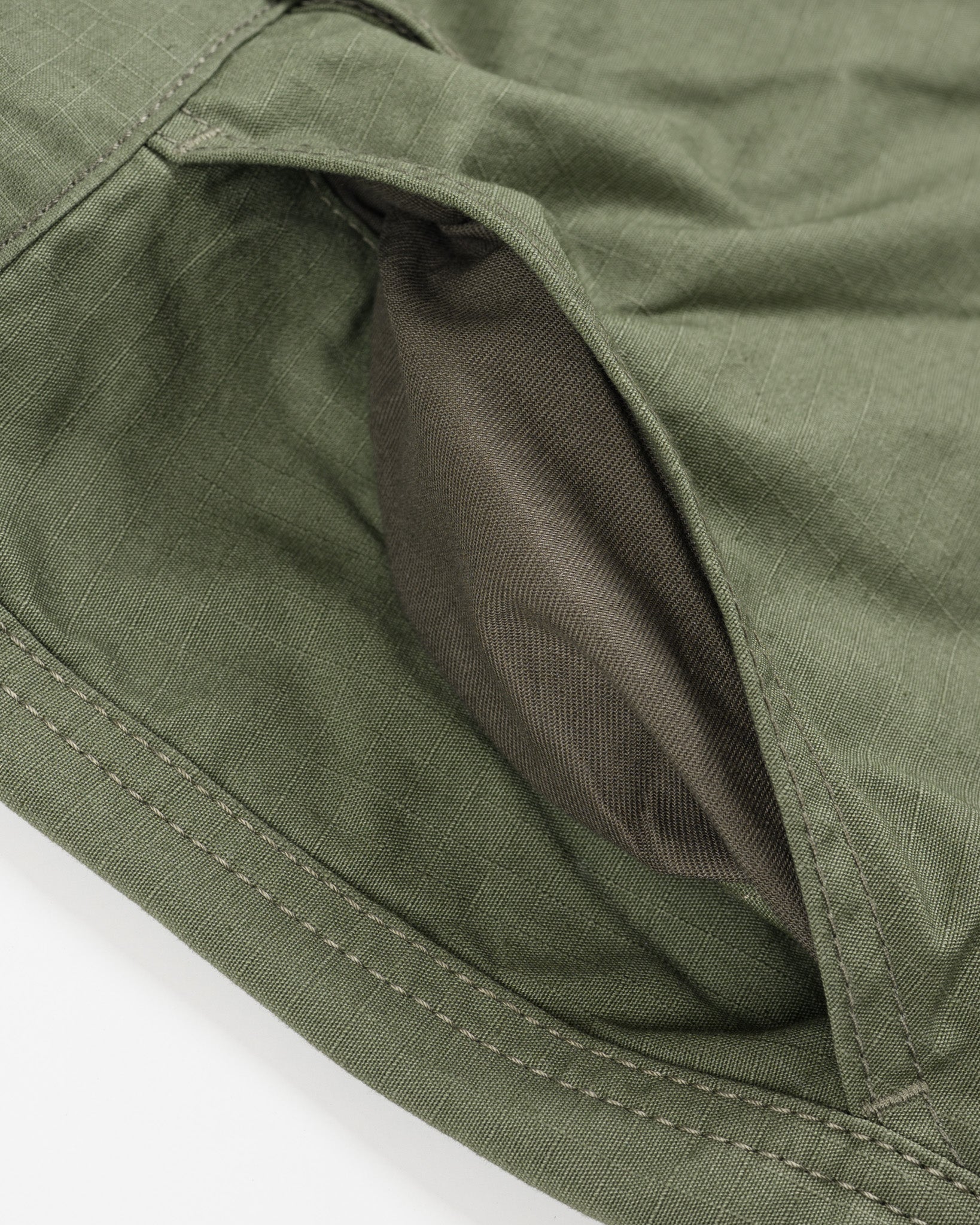 Olive pants laying flat closeup on front pocket