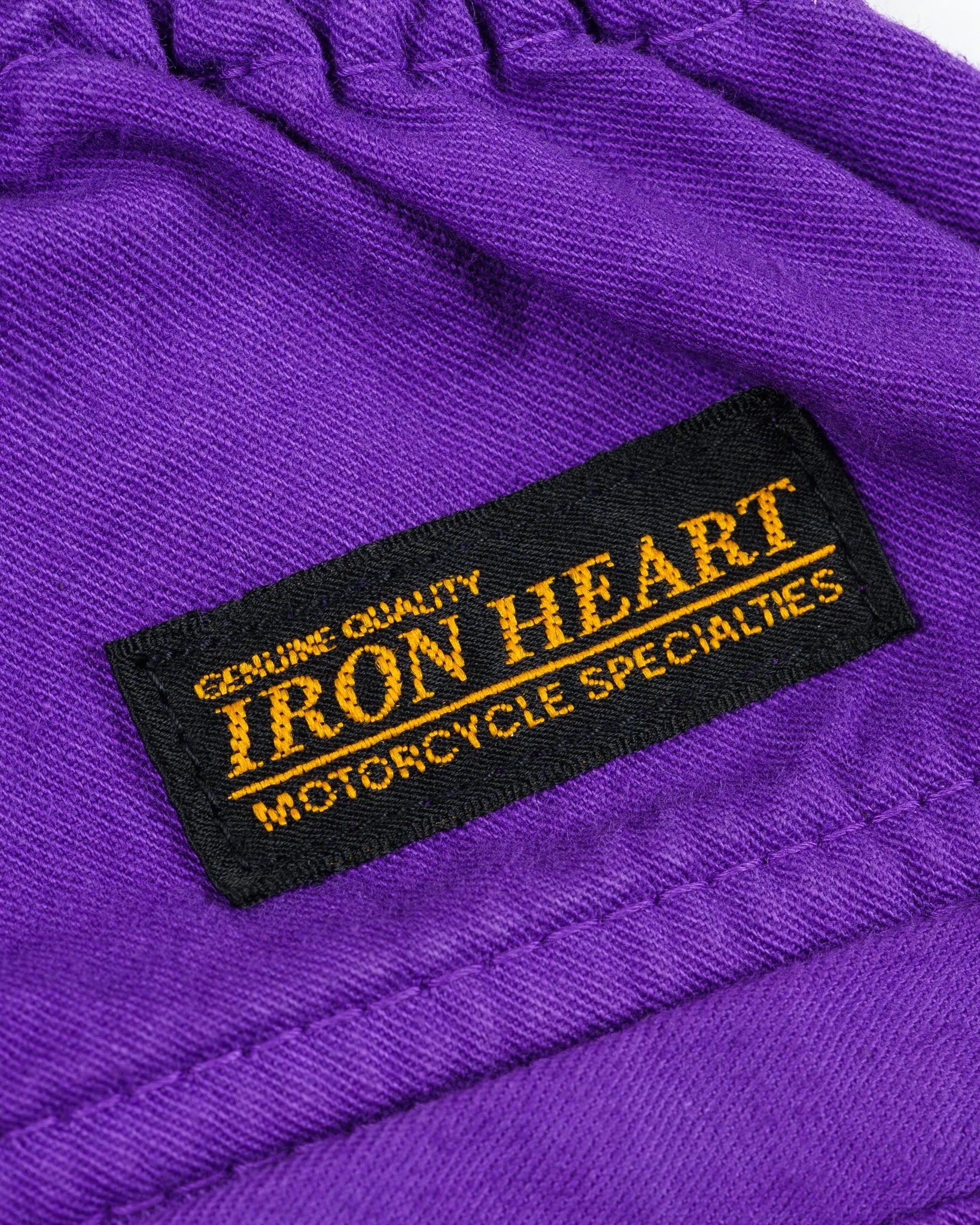 Purple mid length shorts back view laying flat closeup on black/yellow Iron Heart logo