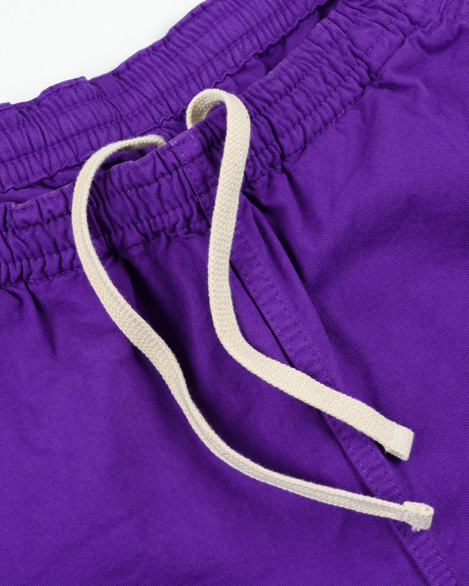 Purple mid length shorts laying flat closeup on white drawstring