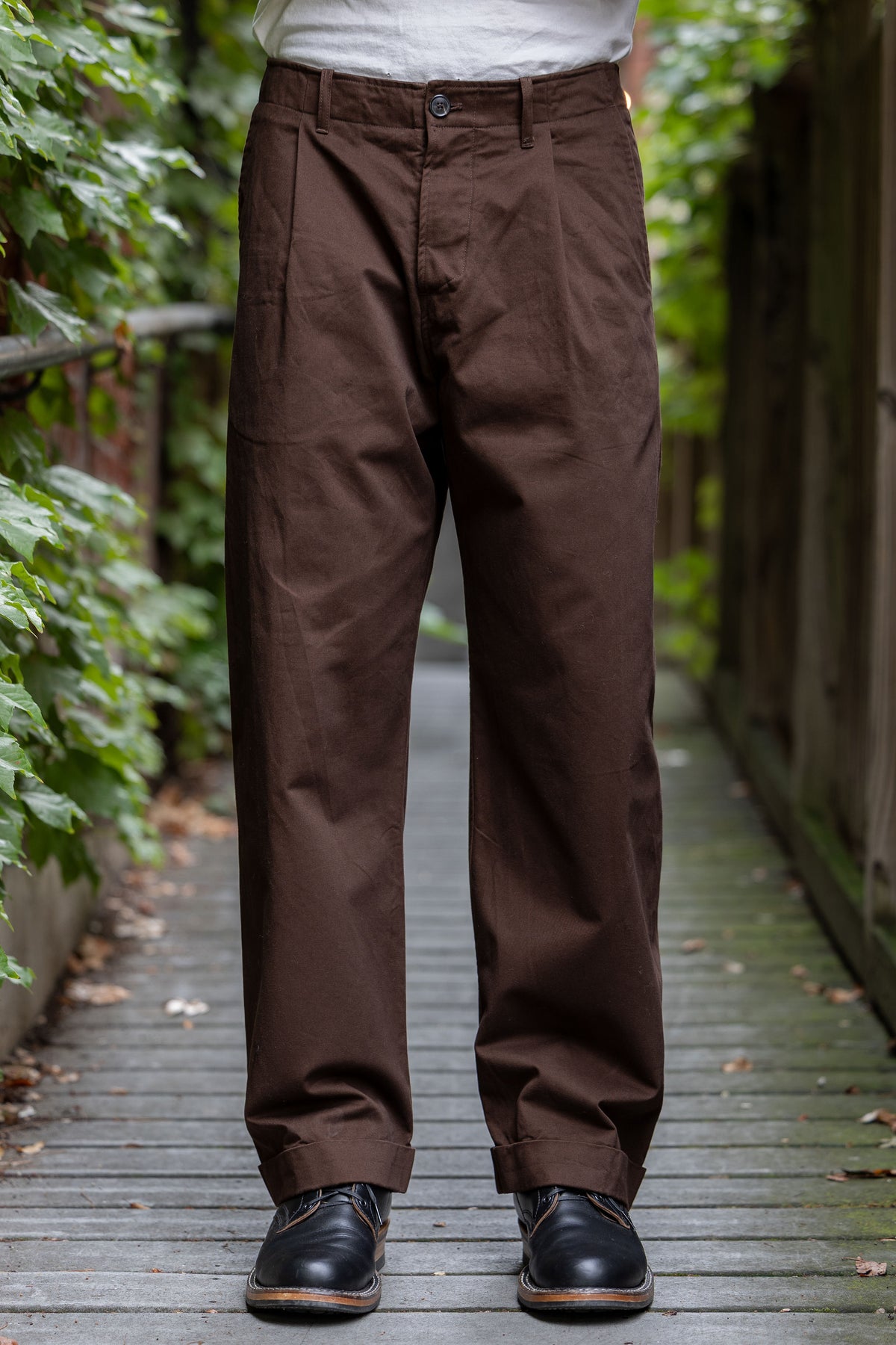 Hansen Garments Bobby Wide Pleated Trousers - Chestnut - model shot - front facing - foliage alleyway backdrop