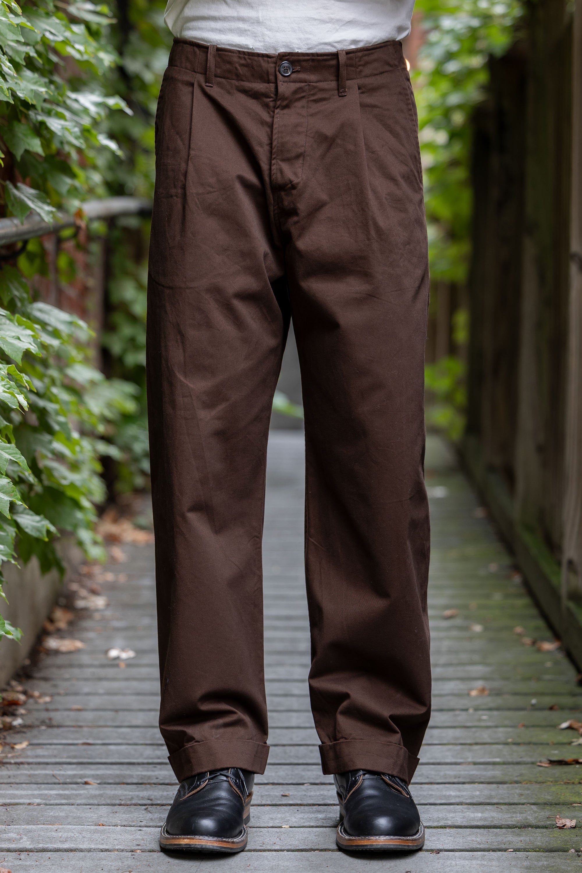 Hansen Garments Bobby Wide Pleated Trousers - Chestnut - model shot - front facing - foliage alleyway backdrop
