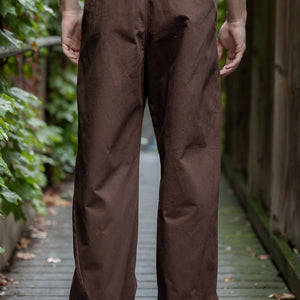 Hansen Garments Bobby Wide Pleated Trousers - Chestnut - model shot - back facing - foliage alleyway background