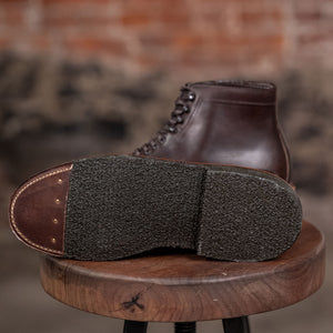 Alden Plain Toe boots on a wooden stool against a brick wall - view of sole