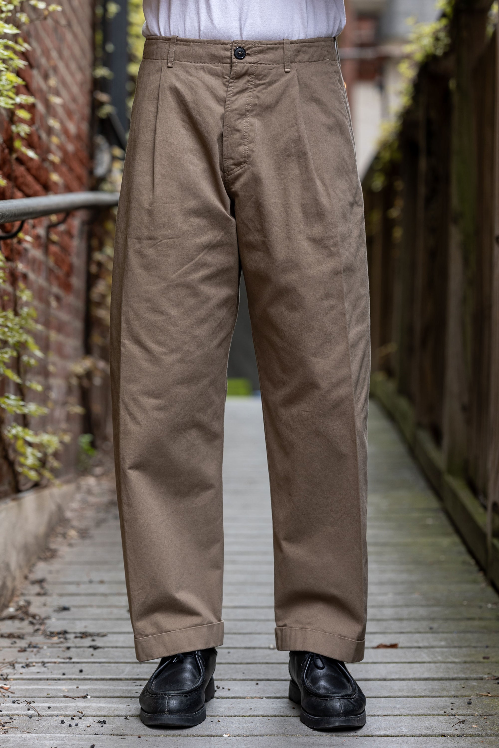 Hansen Garments Bobby Wide Pleated Trousers - Beige - model shot - waist down - front facing - wooden alley background