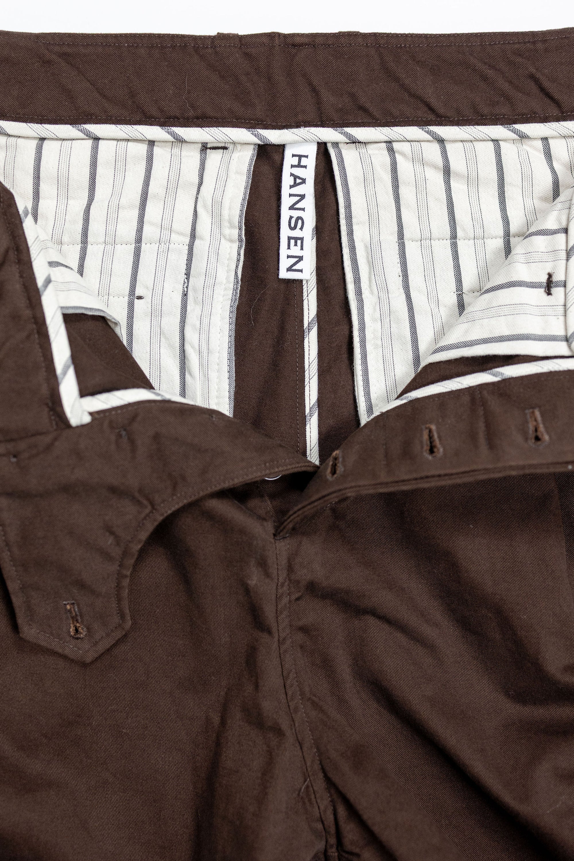 Hansen Garments Bobby Wide Pleated Trousers - Chestnut - product shot - front facing - white background - pants open - detail of buttons, interior, and brand tag