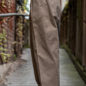 Hansen Garments Bobby Wide Pleated Trousers - Beige - model shot - waist down - side facing - wooden alley background