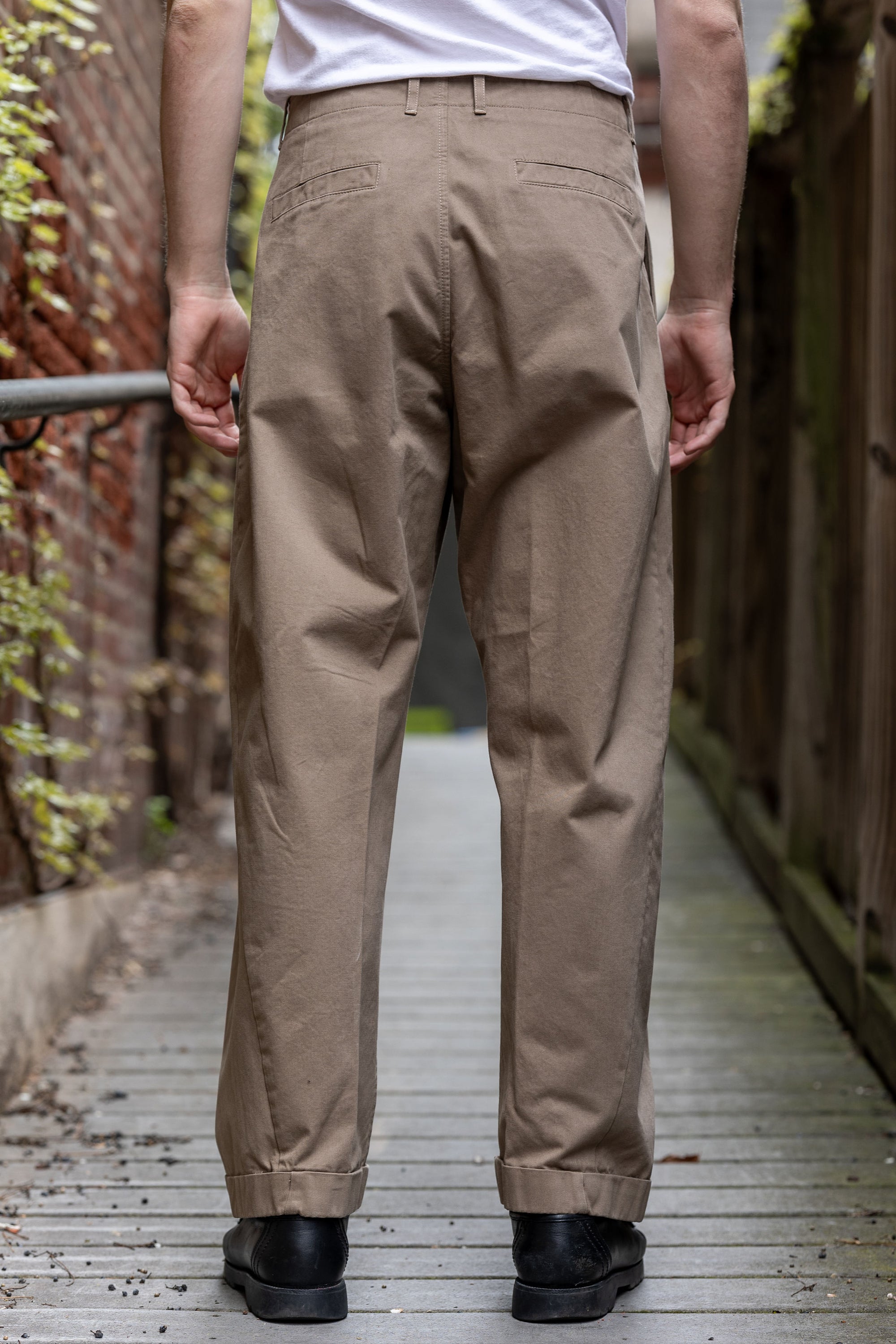 Hansen Garments Bobby Wide Pleated Trousers - Beige - model shot - waist down - back facing - wooden alley background