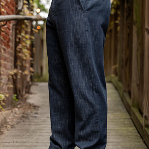 Hansen Garments Trygve Wide Cut Cropped Trousers - Denim Blue - model shot - waist down - side facing - brick & wood alleyway background