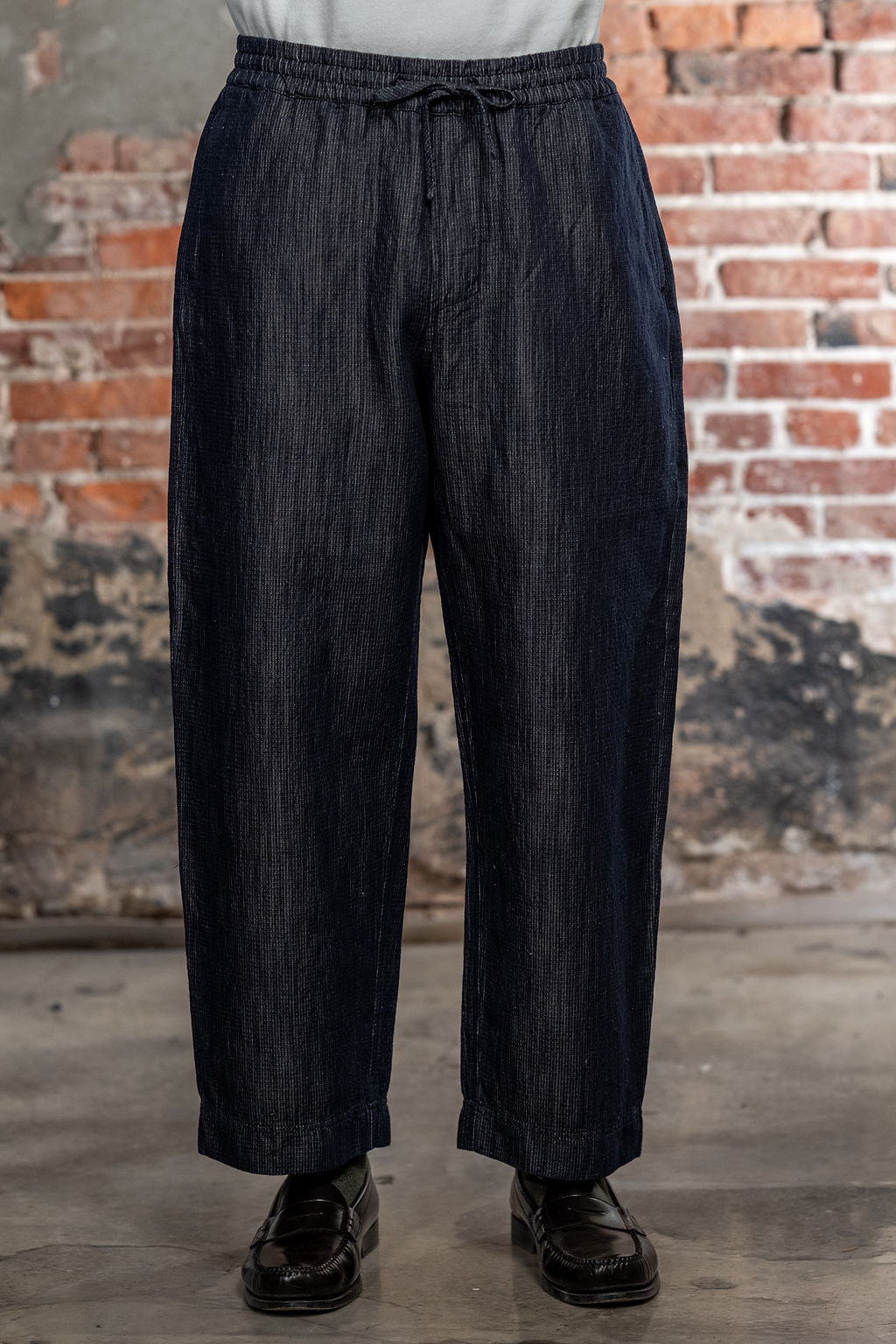 Hansen Garments Emir Loose Drawstring Pants - Navy Dobby - close up - waist down - brick background - front facing