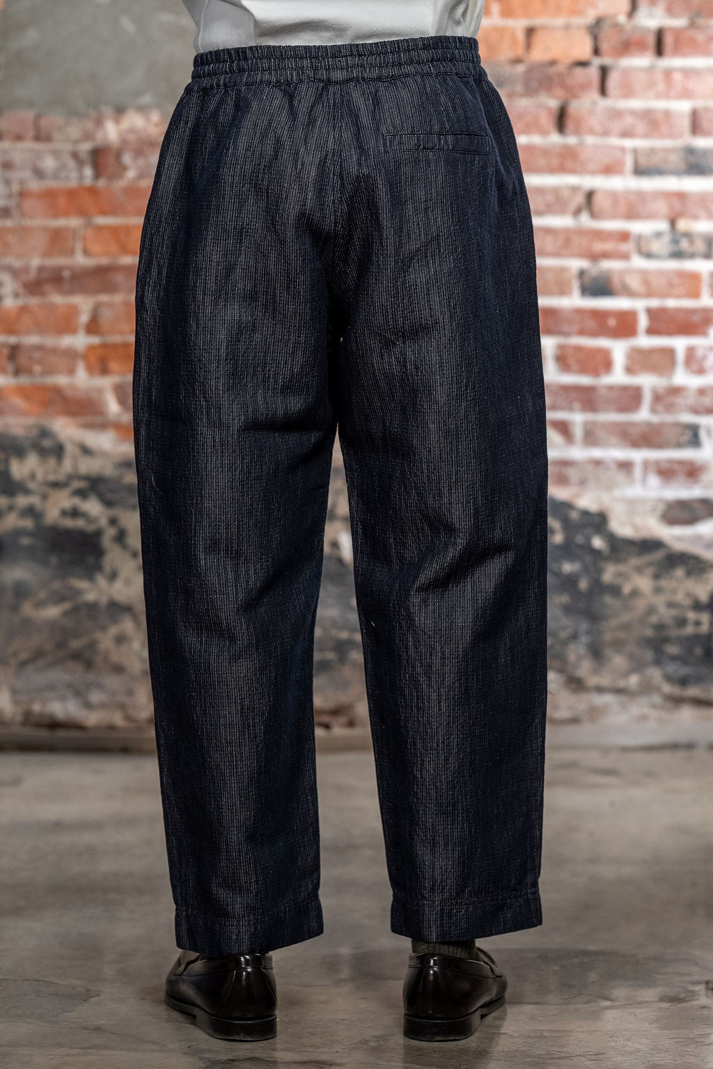 Hansen Garments Emir Loose Drawstring Pants - Navy Dobby - close up - waist down - brick background - back facing