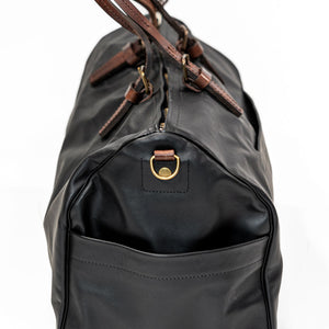 Black leather duffel bag with pockets and brown leather handles side view