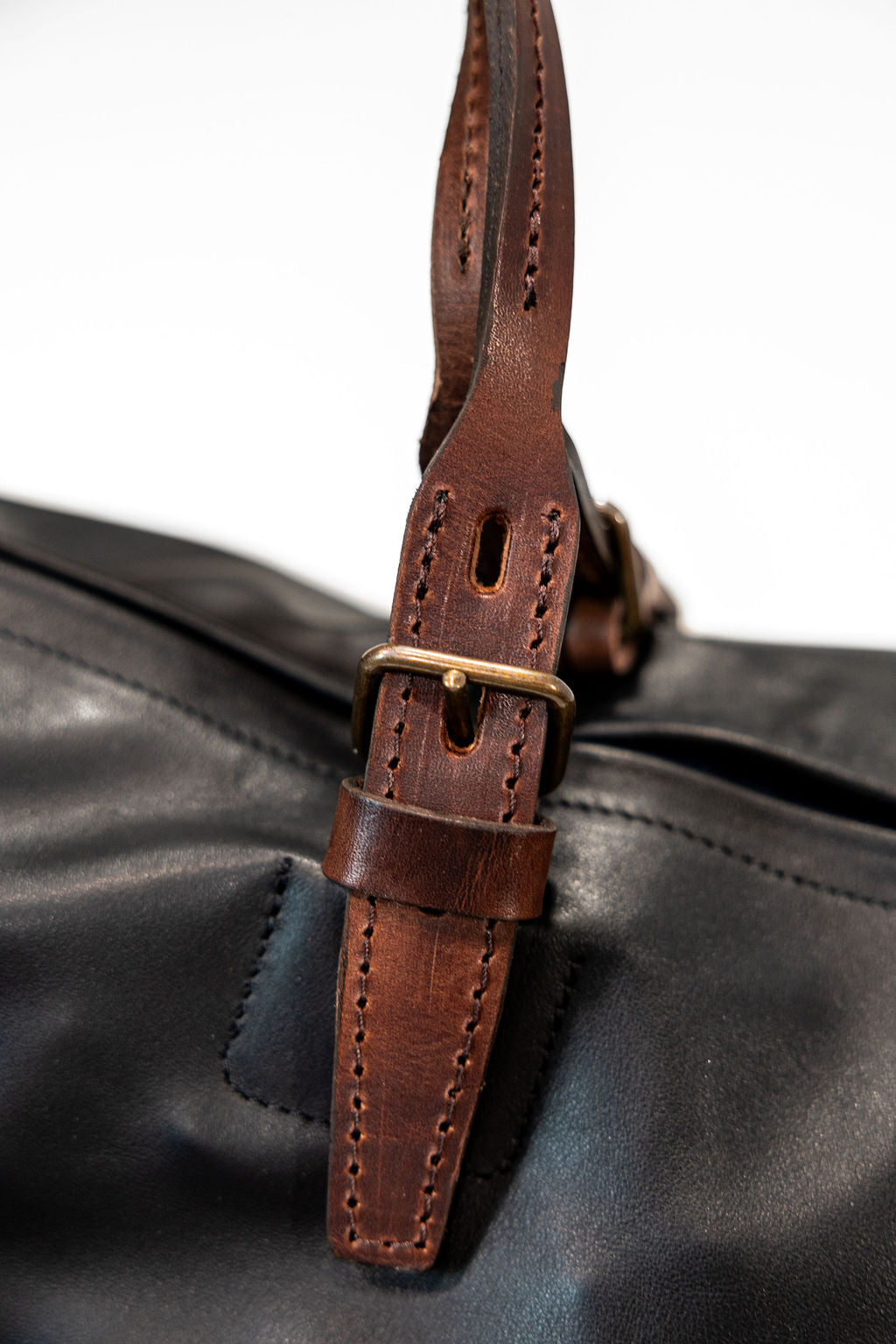 Black duffel bag with brown handles closeup on handle buckle