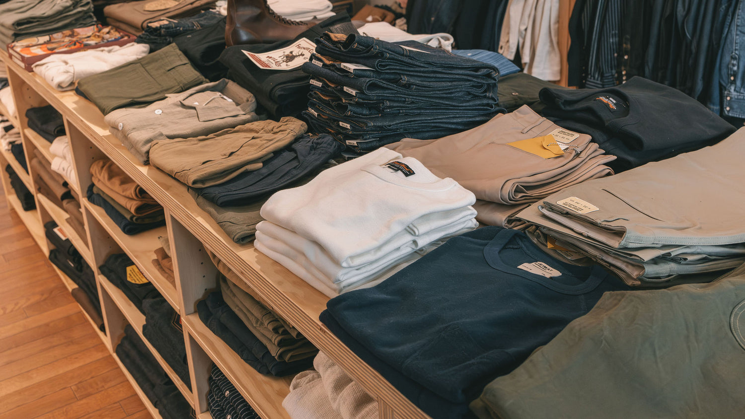 Stacks of folded shirts and denim on wooden shelves inside Franklin and Poe