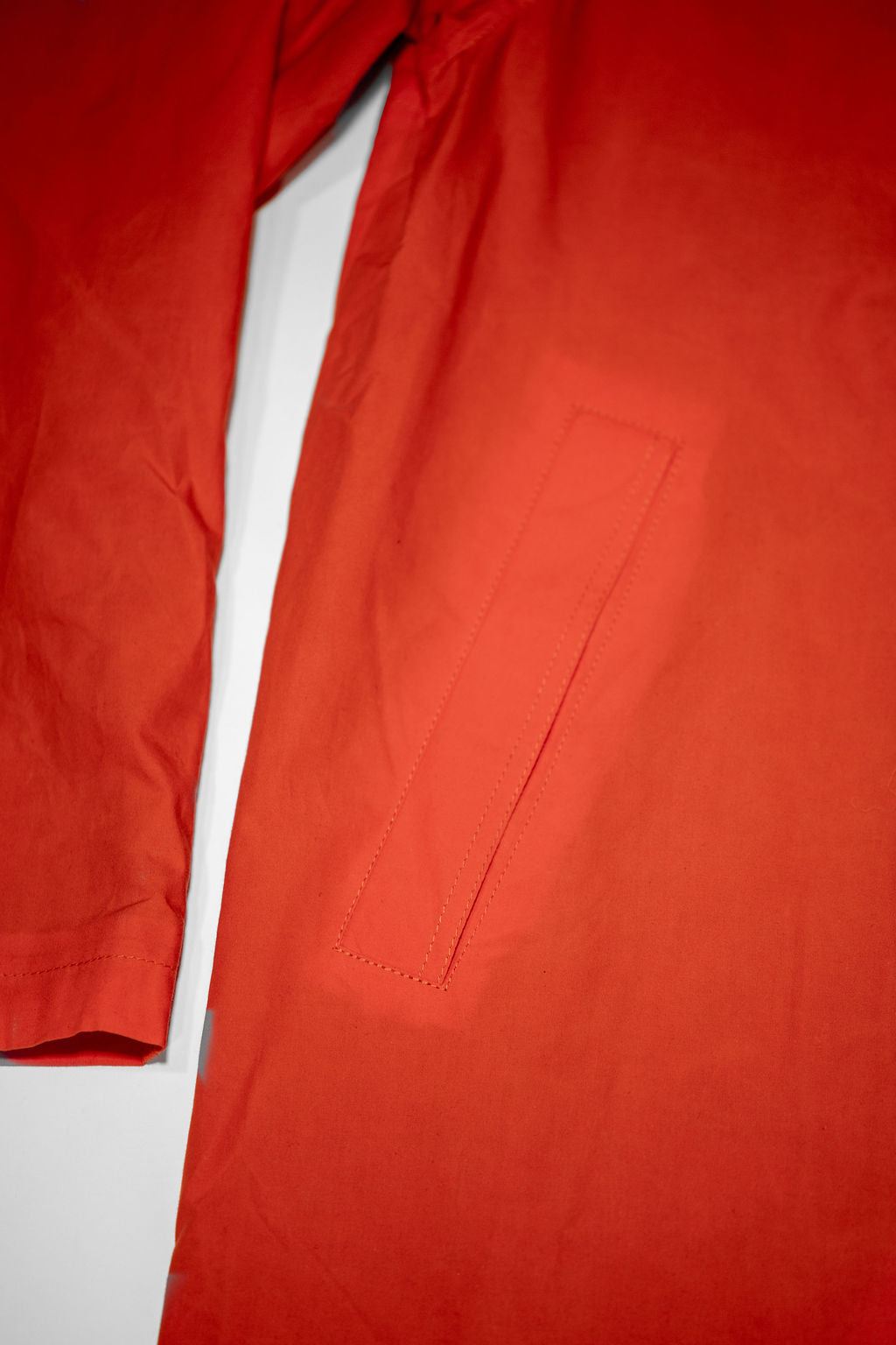 Hansen Garments Morten Long Coat - Waxed Orange laid flat. Details on pocket