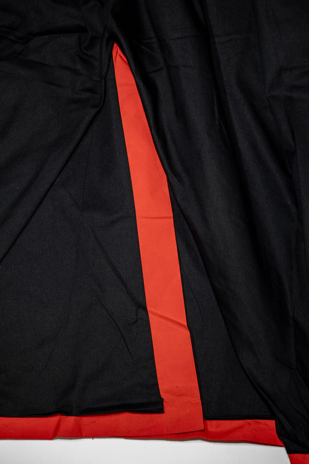 Hansen Garments Morten Long Coat - Waxed Orange laid flat. Details on inside of back slit