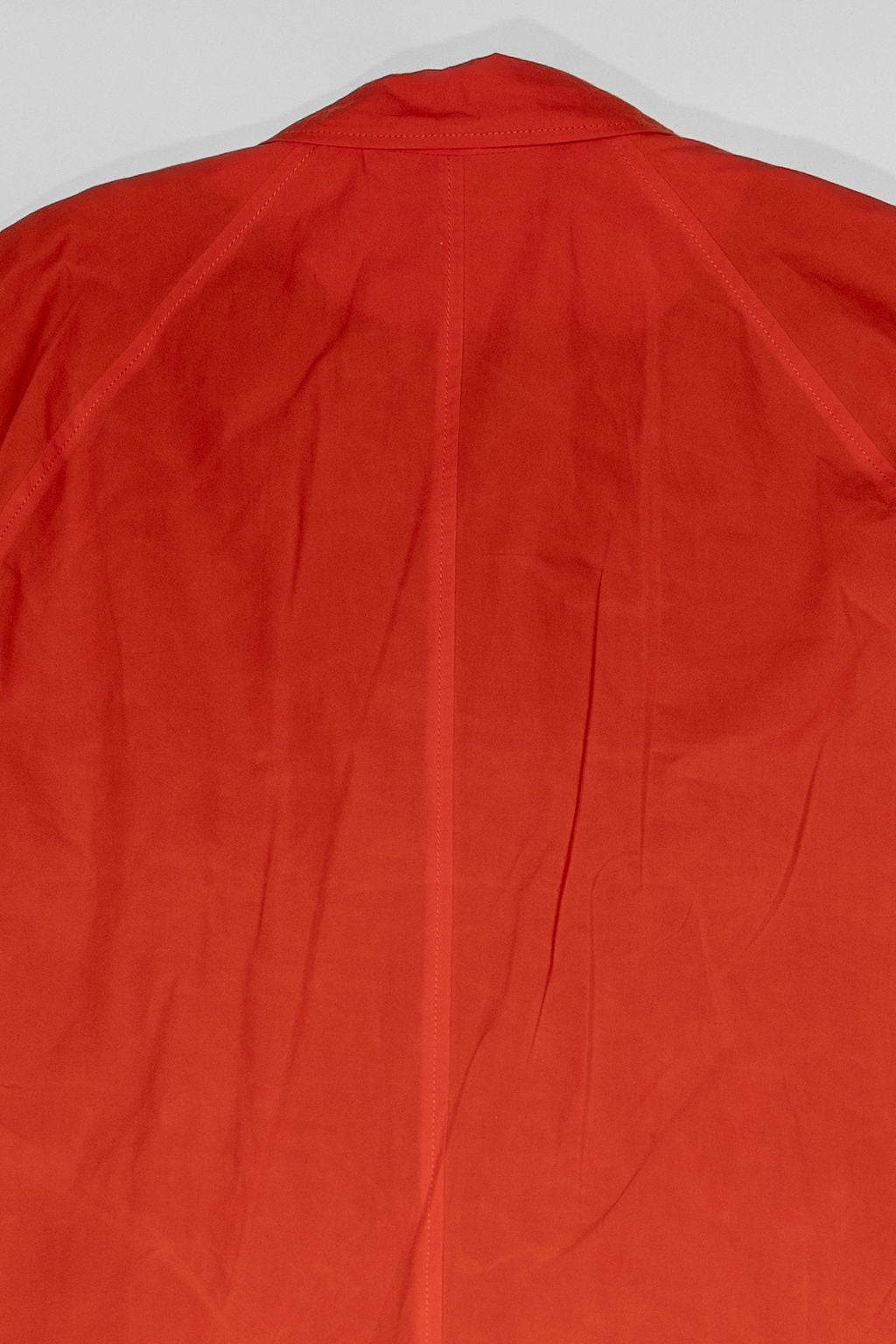 Hansen Garments Morten Long Coat - Waxed Orange laid flat. Details on shoulders and upper back