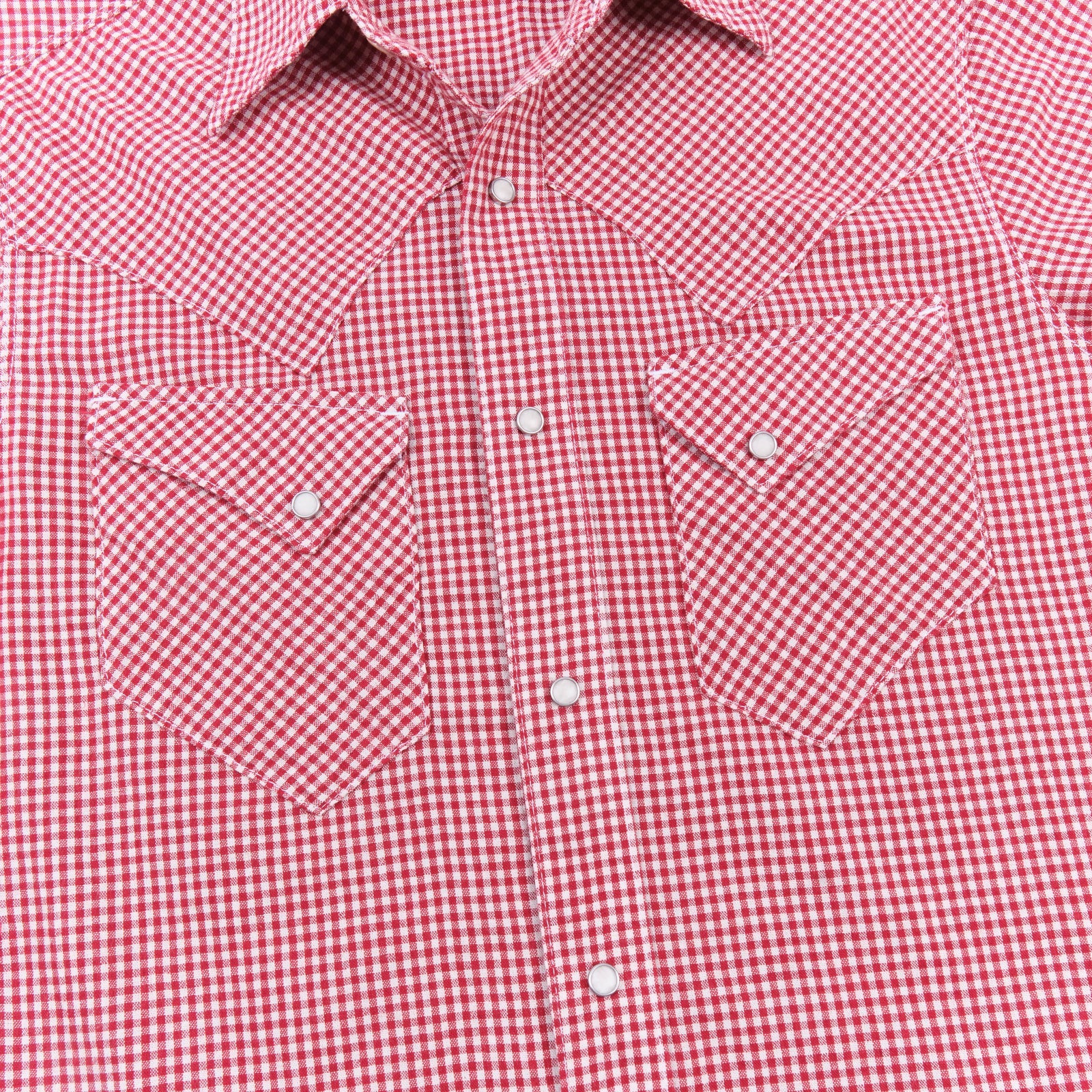 Red and white gingham western-style button-down shirt with two buttoned chest pockets, close up on chest laying flat