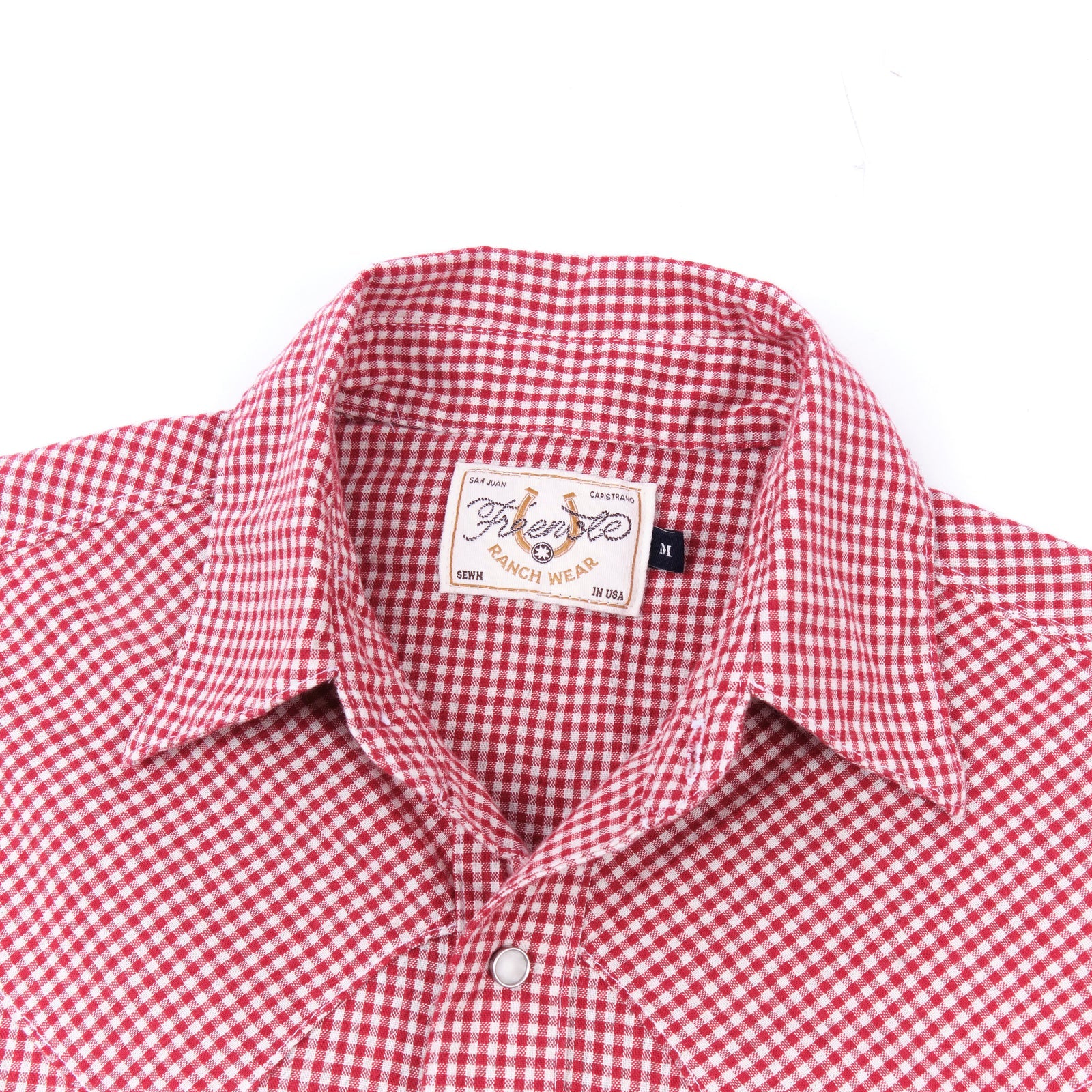 Red and white gingham western-style button-down shirt close up on collar laying flat