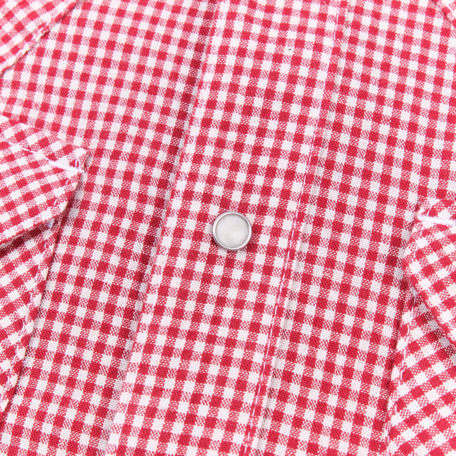 Red and white gingham western-style button-down shirt close up on snap laying flat
