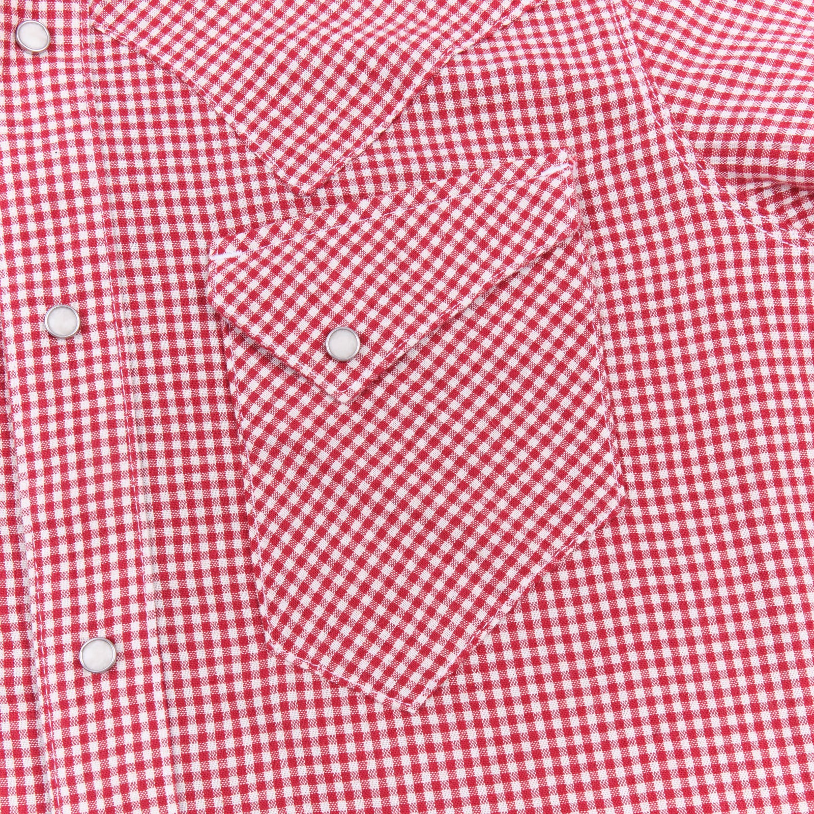 Red and white gingham western-style button-down shirt close up on left chest pocket laying flat