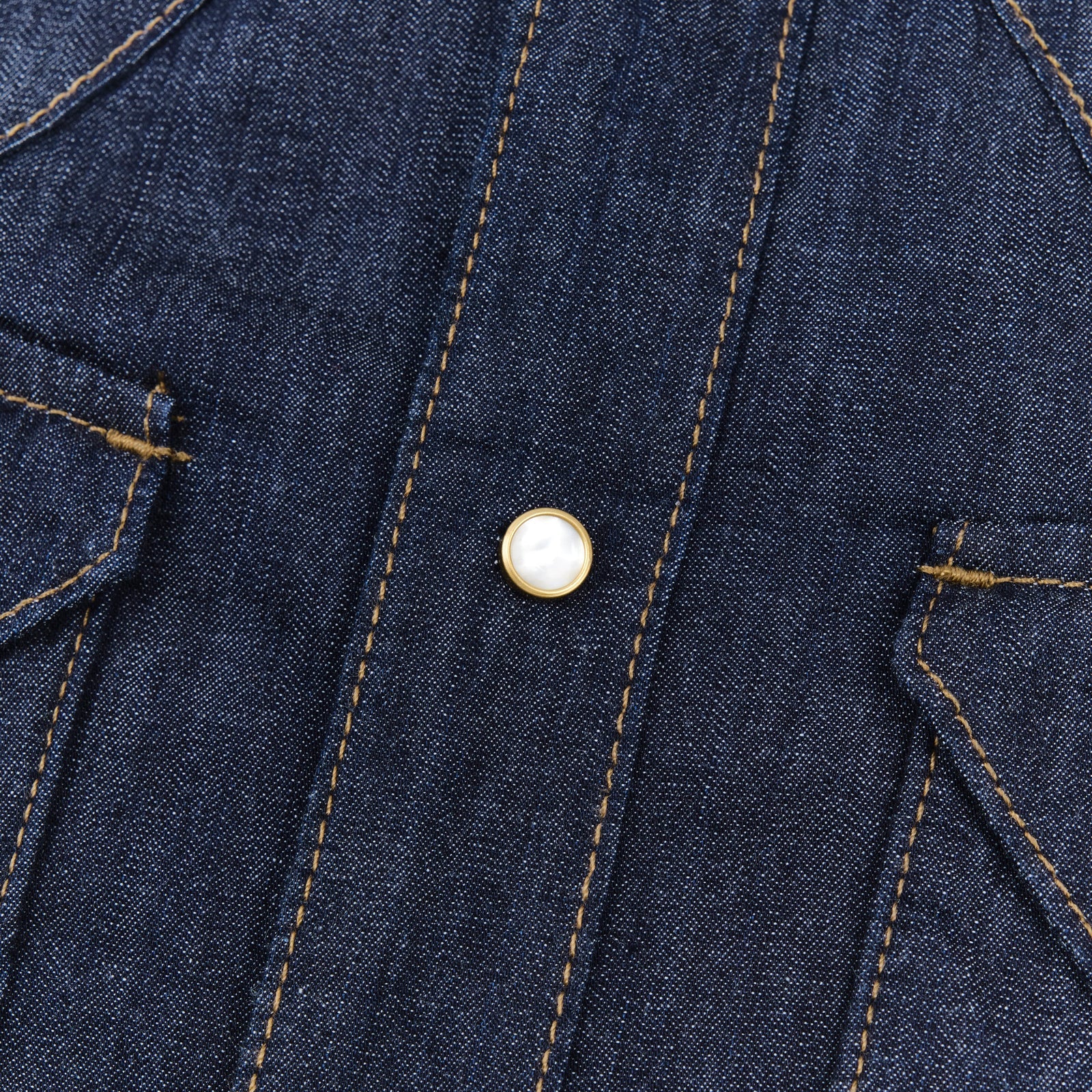 Dark indigo denim western-style shirt with white snaps, close up on snap, laying flat